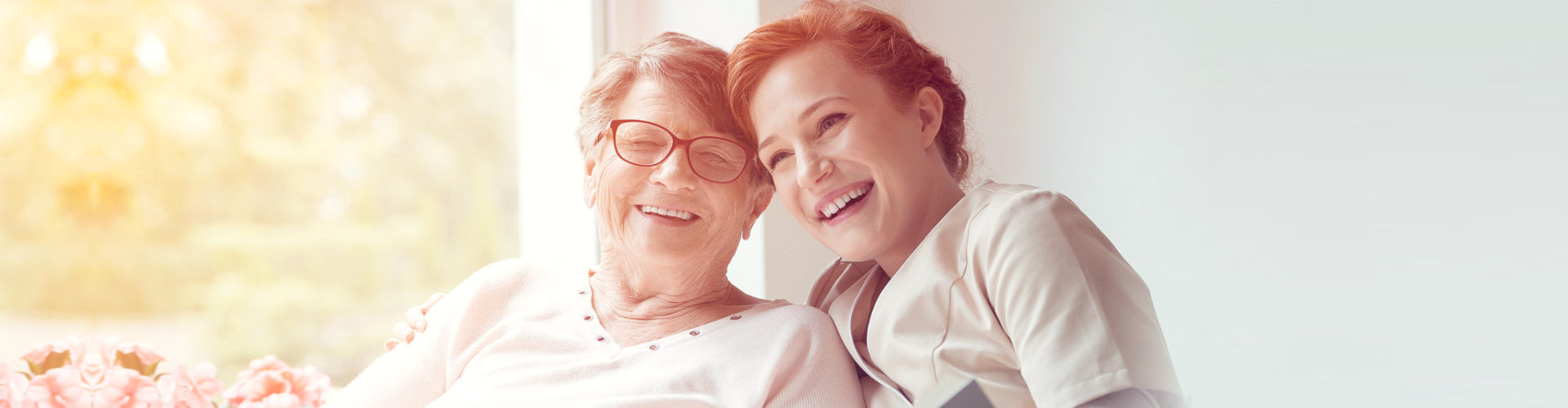 caregiver and an elderly woman smiling at the camera