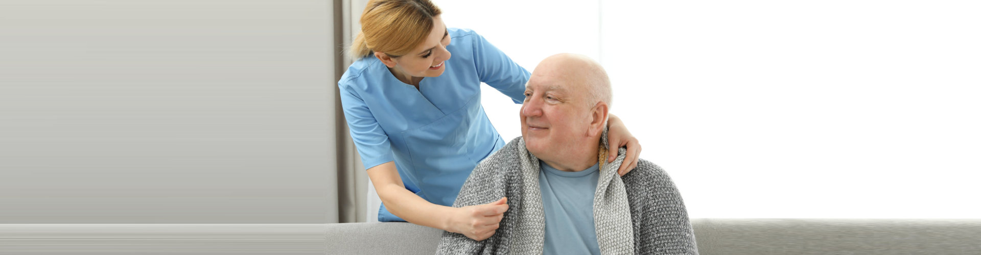 caregiver and an elderly man smiling at each other