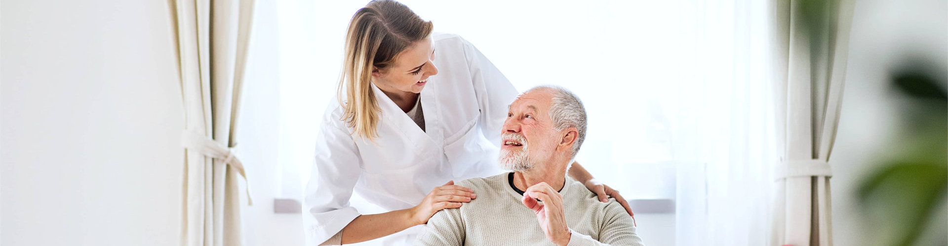 caregiver and an elderly man smiling at each other
